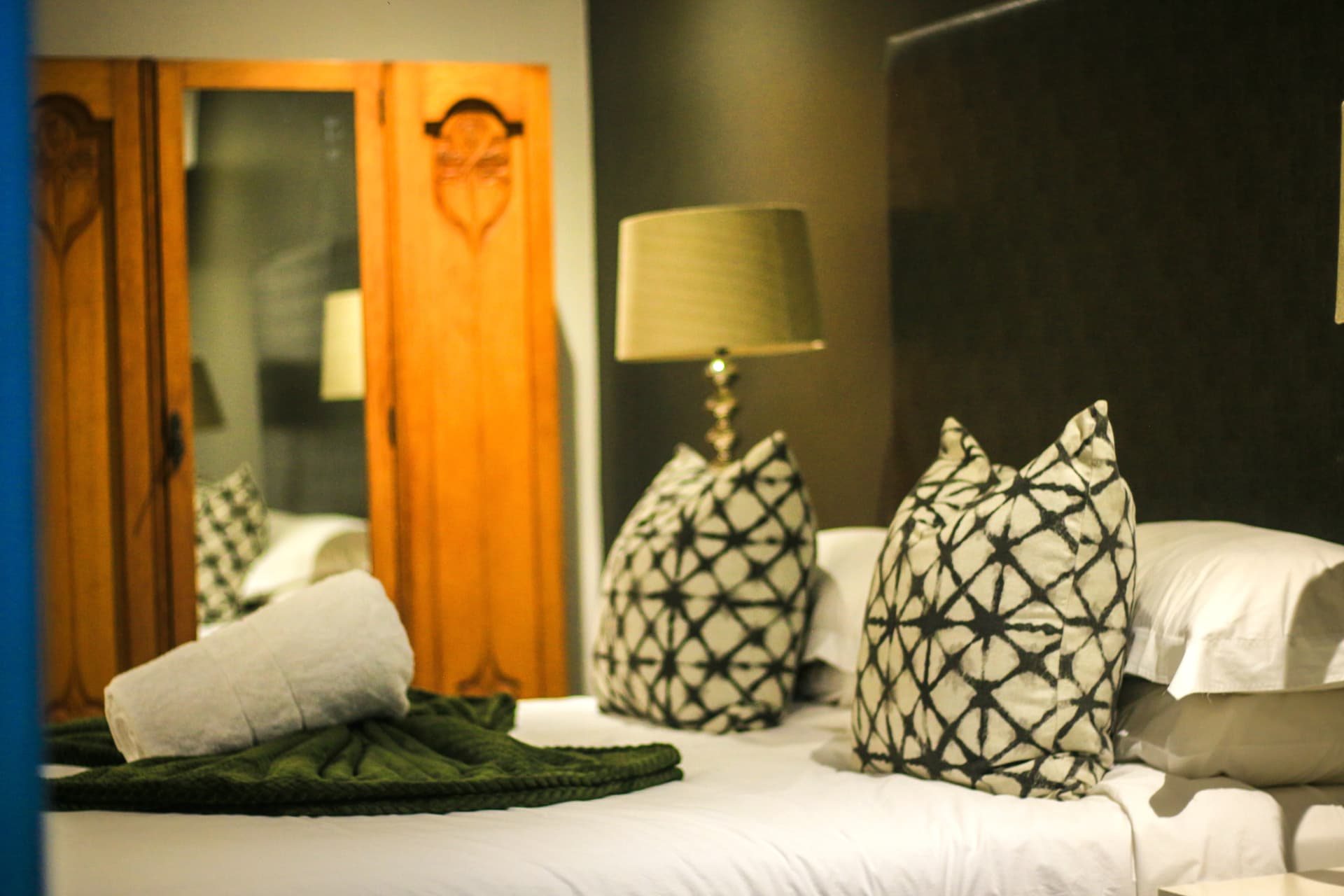 Patterned scatter cushions and rolled towels on a made-up Yellowwoods bed